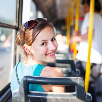 Pretty, young woman on a streetcar/tramway, during her commute to work/school (color toned image  shallow DOF)