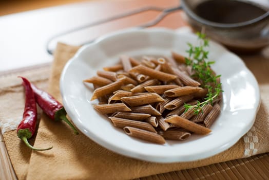 Raw whole pasta with chilli peppers on the table