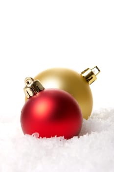 golden and red Christmas baubles on artificial snow with a white background