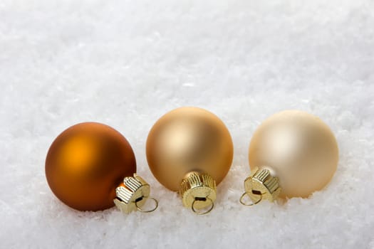 brown,cream and beige Christmas baubles on artificial snow with white background