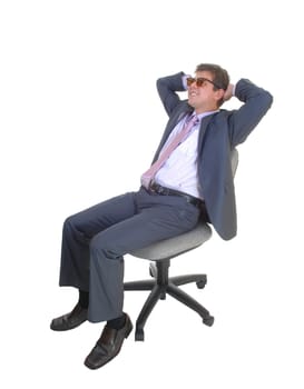 A very happy young businessman sitting on his chair with his hands.behind his head, in a blue suit for white background..