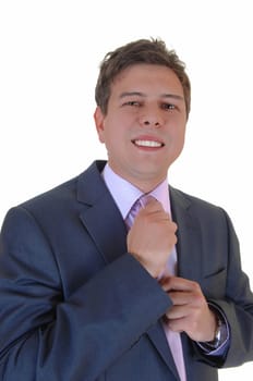 A young businessman in a blue suit fixing his tie, in a closeup for.white background..