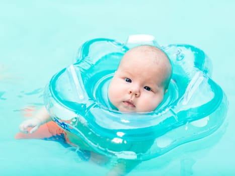 Baby swimming with neck swim ring in pool