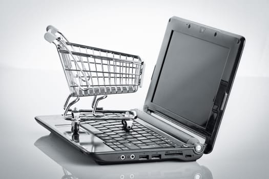 Online shopping. Shopping cart with notebook on the white. shopping cart over a laptop