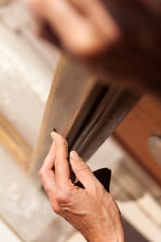Hands of a woman with sandpaper doing DIY work on wooden fixtures