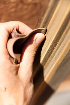 Hands of a woman with sandpaper doing DIY work on wooden fixtures