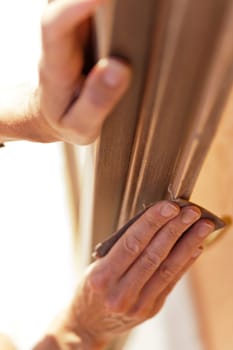 Hands of a woman with sandpaper doing DIY work on wooden fixtures
