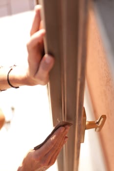 Hands of a woman with sandpaper doing DIY work on wooden fixtures