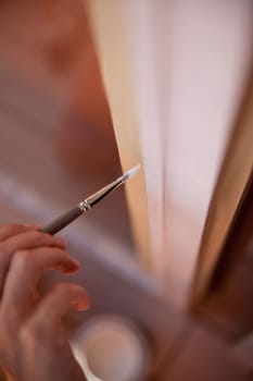 hands of a girl with a paintbrush painting a window as a do-it-yourself job