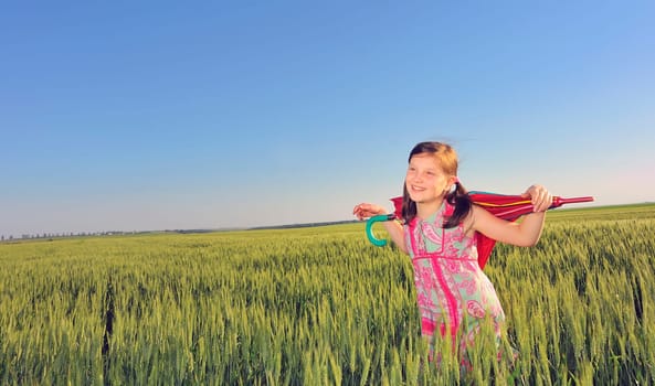a little girl with a umbrella in green field
