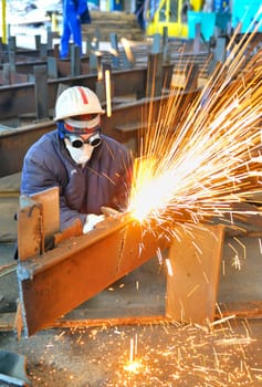 worker using torch cutter to cut through metal in factory
