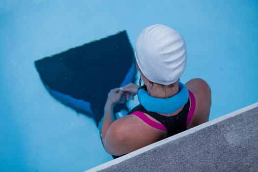 Female freediver with monofin concentrating and preparing at edge swimming pool