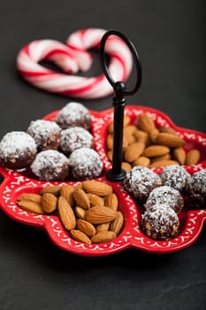 Closeup of tray of almonds and chocolate balls with hard handy heart with red swirls in background