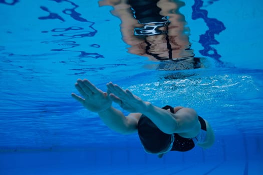 Female swimmer diving underwater in swimming pool