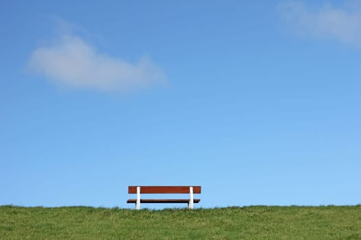 Bank on a dike on the North Sea,under blue,clear skies