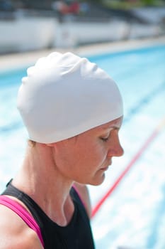 Female swimmer beside swimming pool concentrating with eyes closed