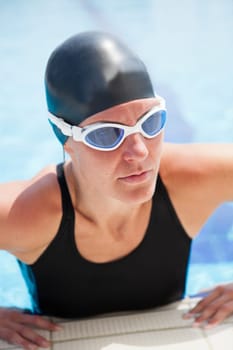 Female swimmer at edge swimming pool and preparing to lift herself out