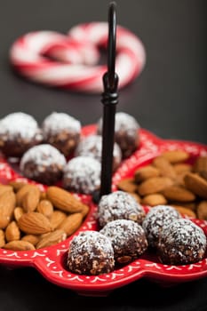 Closeup of tray of almonds and chocolate balls with hard handy heart with red swirls in background