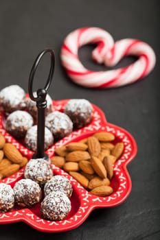 Closeup of tray of almonds and chocolate balls with hard handy heart with red swirls in background