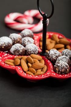 Closeup of tray of almonds and chocolate balls with hard handy heart with red swirls in background