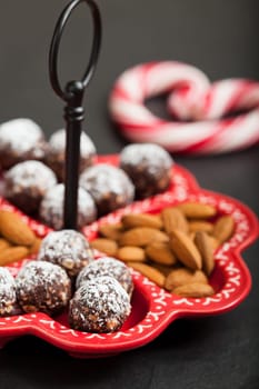 Closeup of tray of almonds and chocolate balls with hard handy heart with red swirls in background