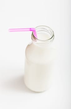 Closeup of fresh milk in glass jar with pink straw on light background