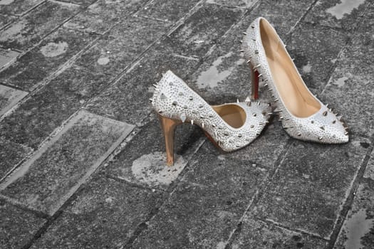 Silver spiked brides shoes over rural floor