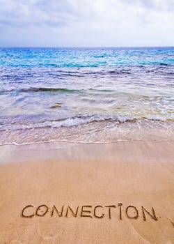 Connection word written on sand, with waves in background, connecting concept