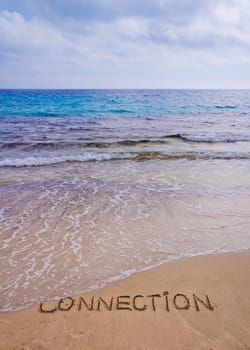 Connection word written on sand, with waves in background, connecting concept