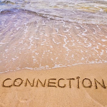 Connection word written on sand, with waves in background, connecting concept