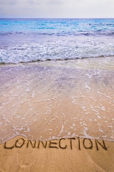 Connection word written on sand, with waves in background, connecting concept