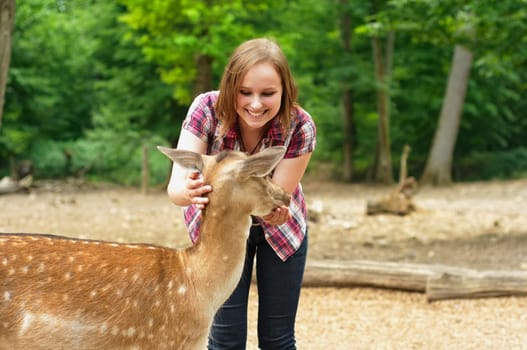 Woman feeds and pets a young deer