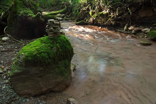 Stone man in a forest by a river