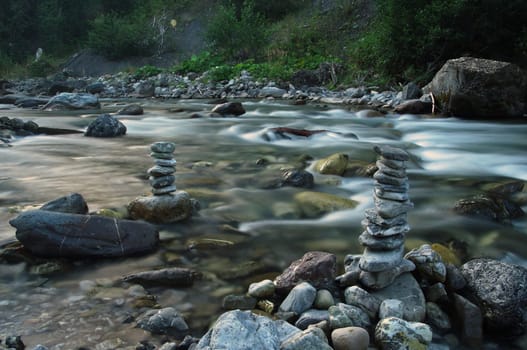 Two stone men in a river with stones