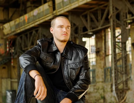 Young man with a leather jacket in an abandoned hall