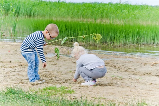 Boy and girl playing in the sand on the shore of Lake