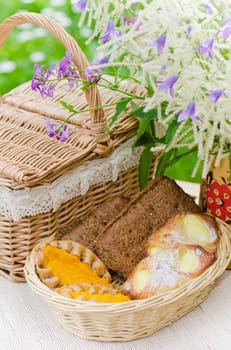 Buns in a wicker basket and a bouquet of field flowers