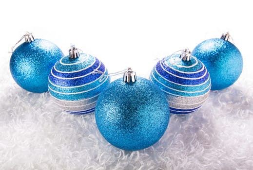 Blue christmas balls white fur background.