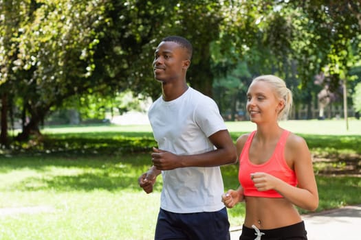 Two sporty young joggers running in the park in summer training health