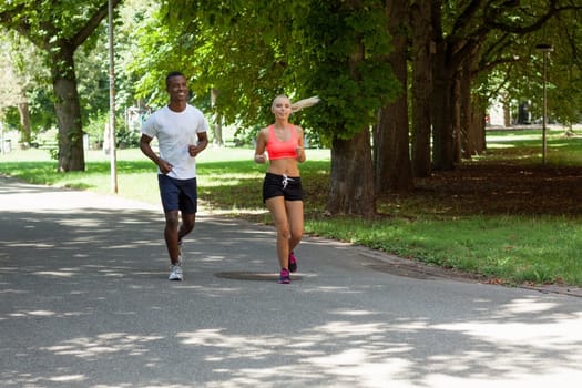 Two sporty young joggers running in the park in summer training health