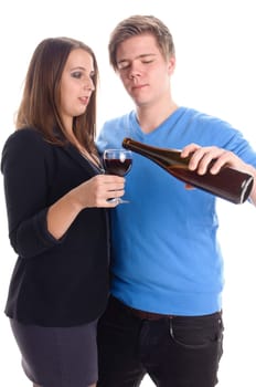 A young man and a young woman stand next to each other,she holds a glass of wine and he holds a wine bottle in his hand. Cropped against a white background.