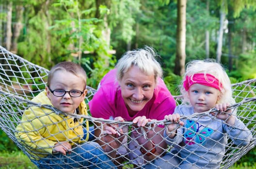 Children with grandmother swinging in a hammock, close-up