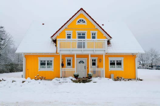 Yellow wooden house in Nordic style frontal,covered with lots of snow in winter.