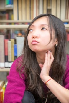 Portrait of young woman in front of book shelf