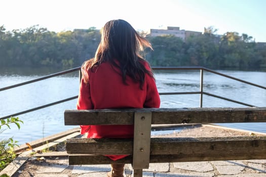 Young woman sitting on a wooden chair next to river
