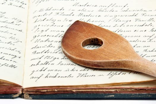Old cookbook with wooden spoon
