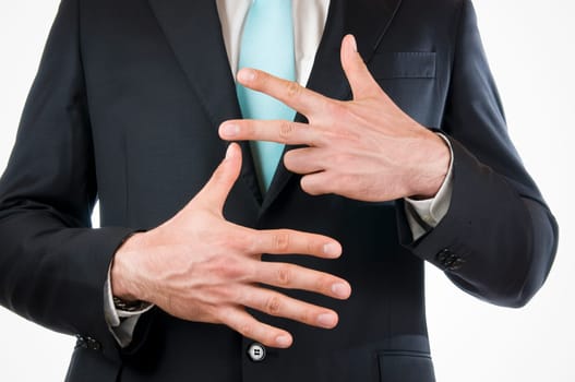 Chest-and-stomach view of a young man in a black suit with his hands held in front of him indicating the "8"" (eight fingers)"