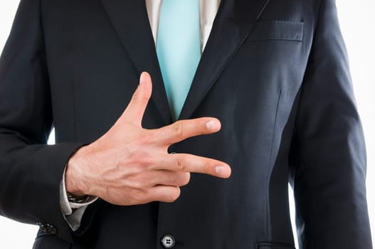 Chest-and-stomach view of a young man in a black suit with his right hand held in front of him indicating the "3"" (three fingers)"