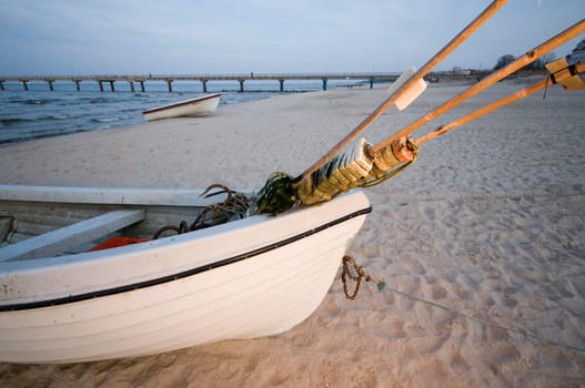 Detail view of a small fishing boat on the Baltic Sea Beach at sunset on the island of Usedom in the summer  Pier in the blurry background.