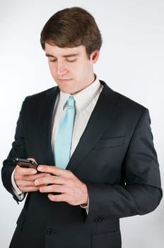 Waist up a young man in a black suit against white background with forward looking holding their smart phone on the display.
